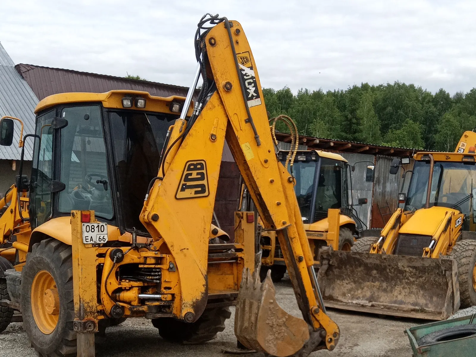 JCB 3CX с разложенной экскаваторной стрелой на выносных опорах
